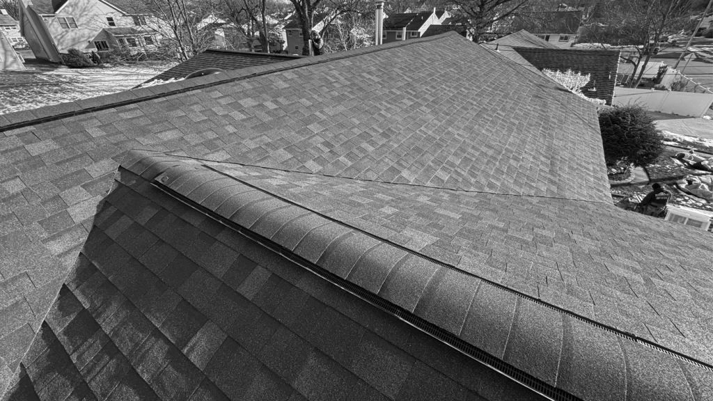 black and white image at Peak of asphalt Shingle Roof in winter